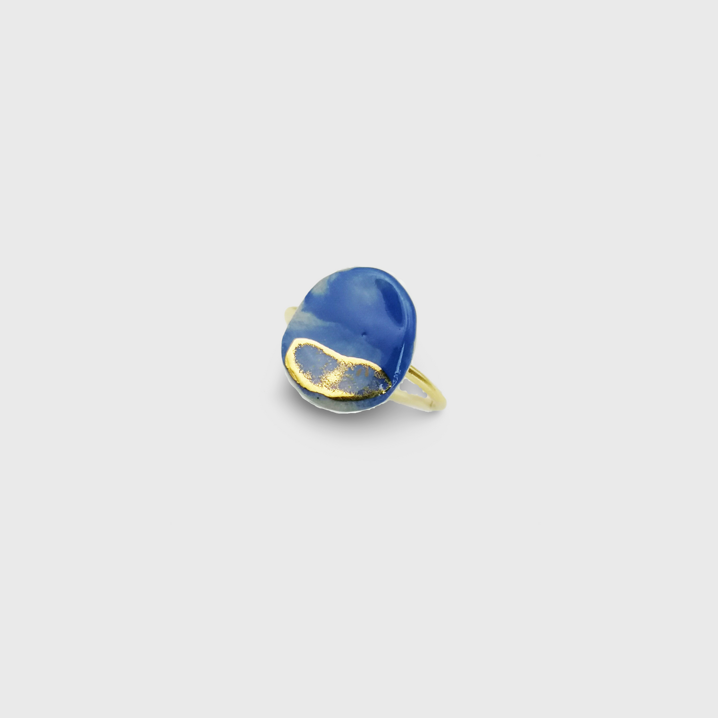 Bague artisanale en céramique bleu roi et or, présentée dans un élégant écrin rose.