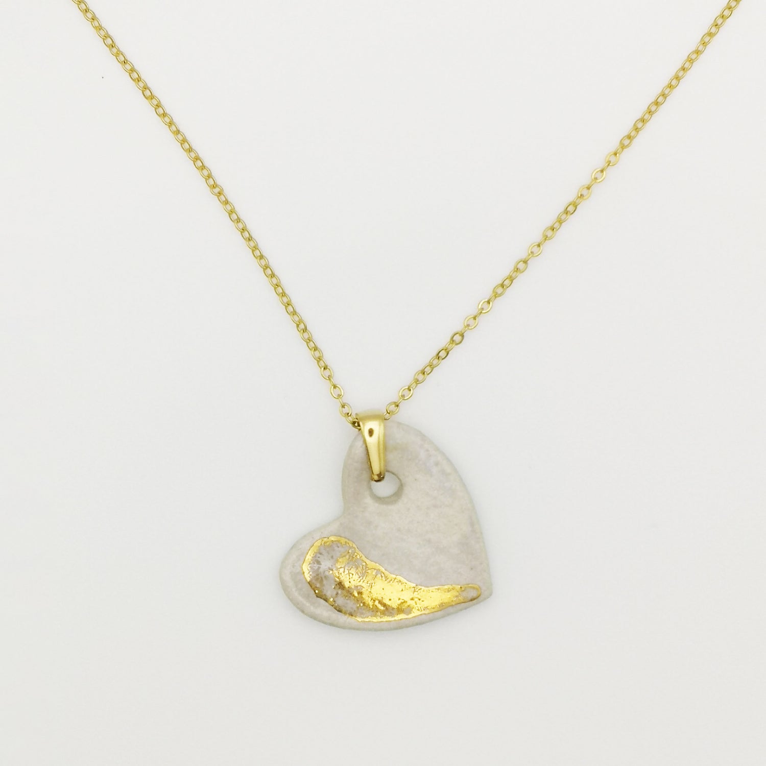 Collier cœur en céramique blanche nacrée et or avec chaîne en laiton doré, présenté sur fond neutre pour femme fait main à Aix en Provence