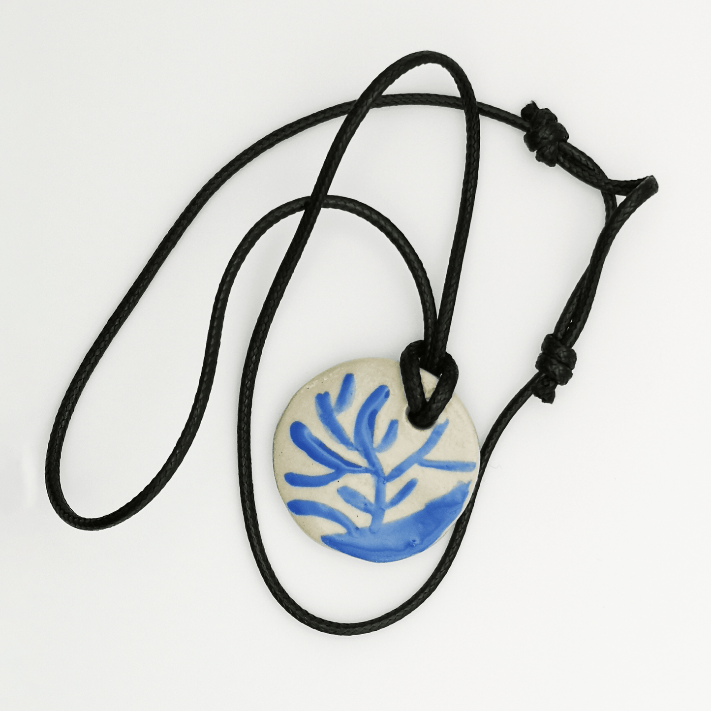 Collier médaillon en céramique blanc et bleu avec motif branche dorée, sur long cordon en cuir réglable, inspiration nature, bijou artisanal unique de Corinne Céramique