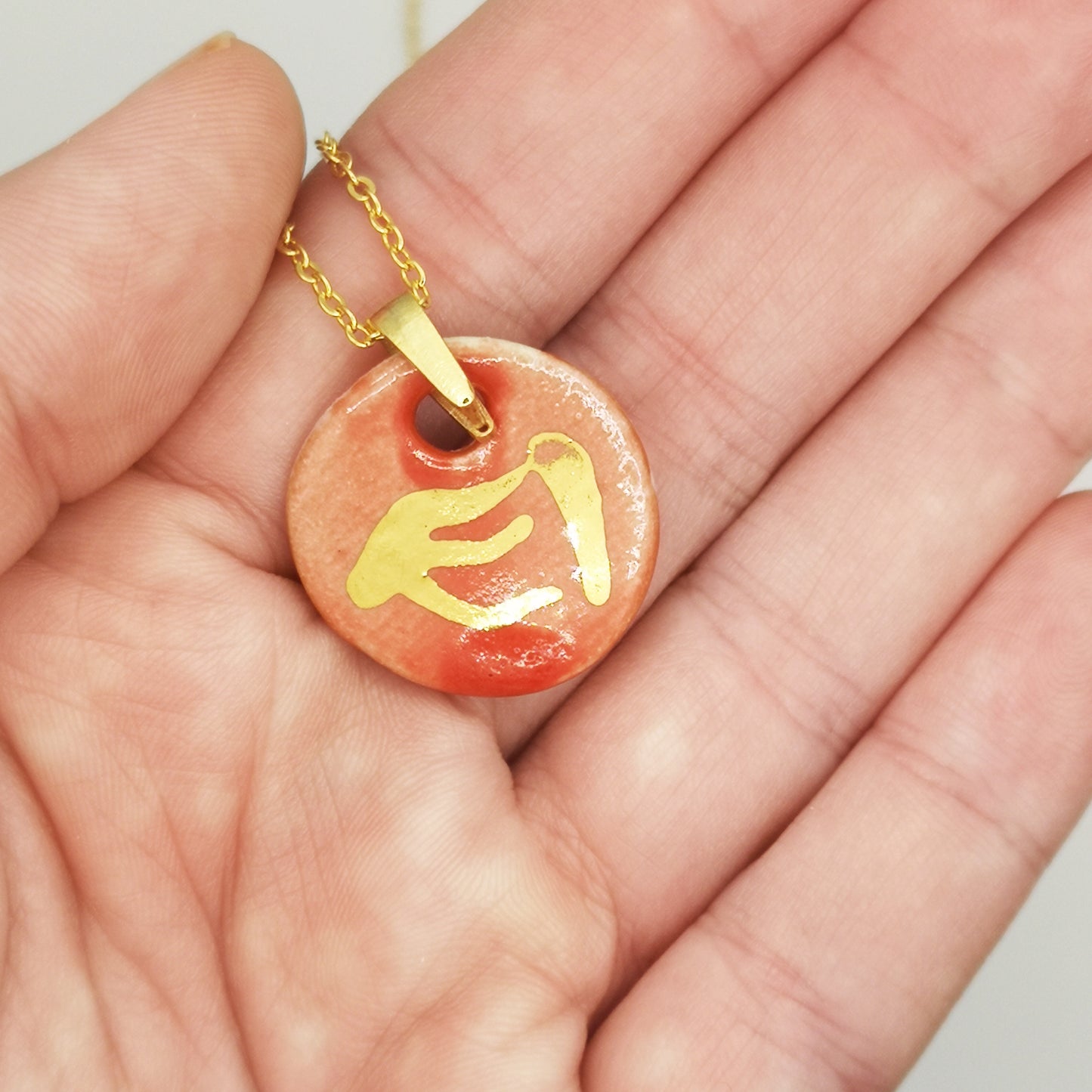Collier médaillon en céramique rouge corail, création artisanale française avec design phénix en or.