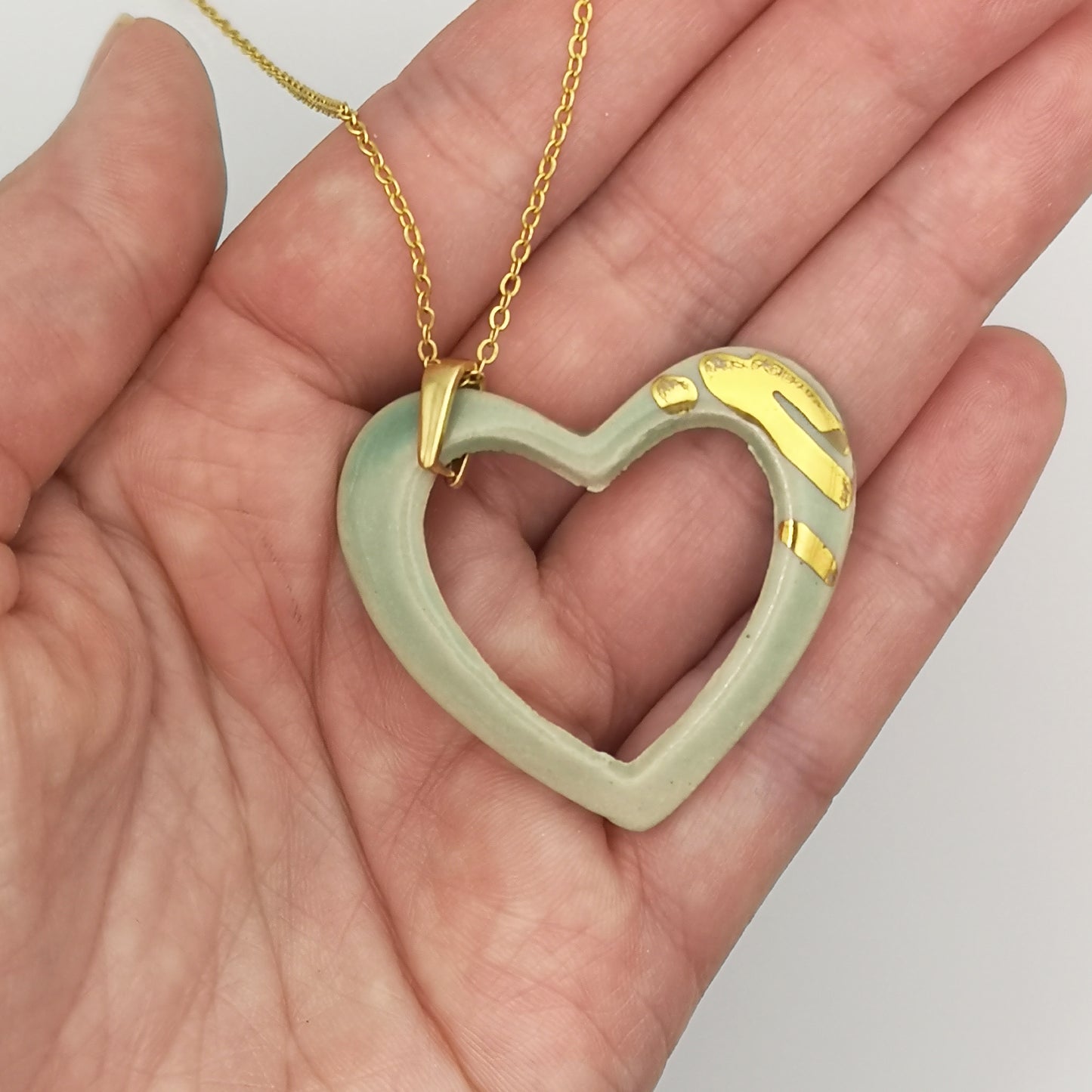 Collier Coeur vert or avec chaine moderne pour femme corinne ceramique aix en provence artisan dans une main