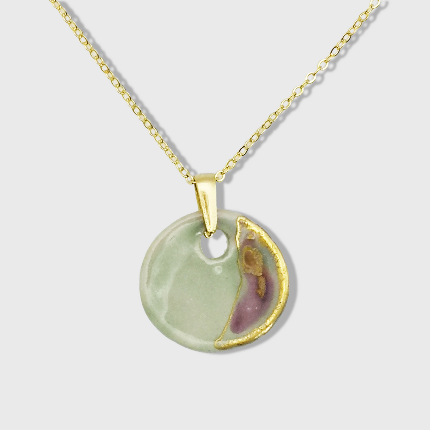 Collier médaillon en céramique vert céladon et or, suspendu à une chaîne dorée à l'or fin 24K. Bijou élégant et raffiné, fait main en France.