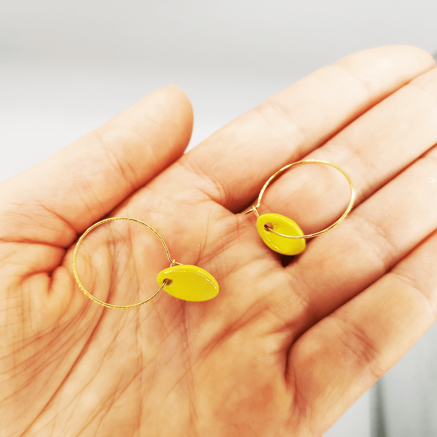 boucles d'oreilles jaune petite pendante dans main