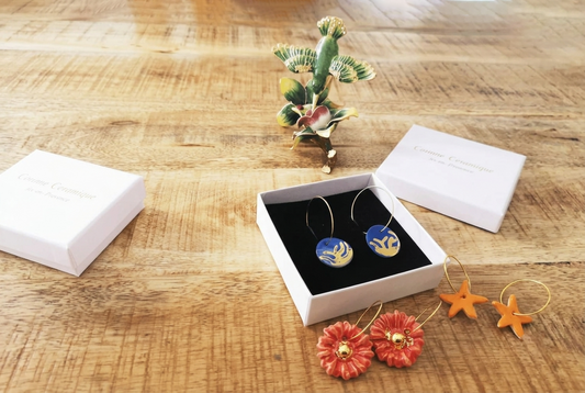 Boucles d'oreilles en céramique faites main Corinne Céramique, plusieurs paires colorées présentées avec un écrin cadeau de luxe ouvert, bijoux artisanaux fabriqués à Aix-en-Provence