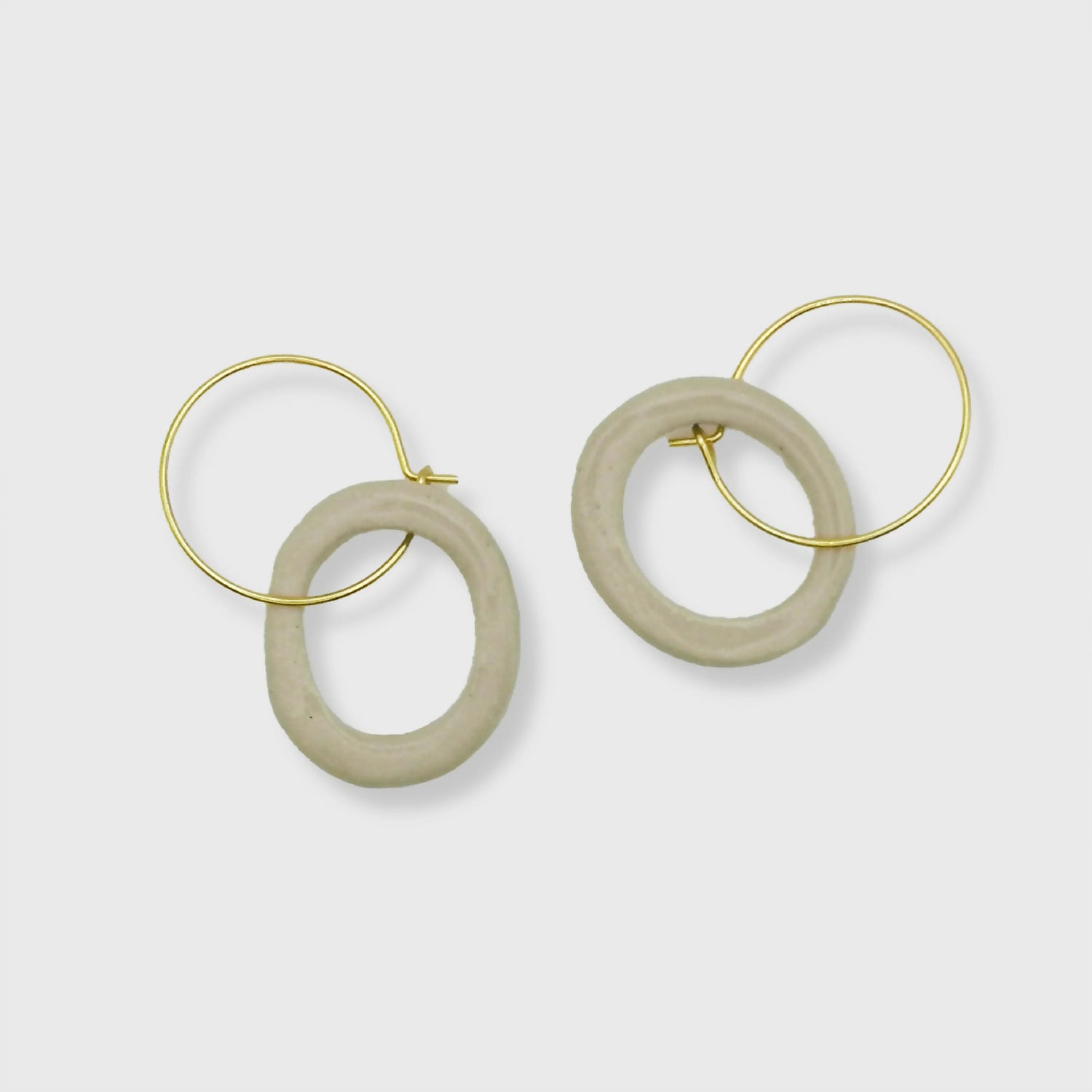 Boucles d'oreilles en céramique blanc argile sur fond neutre - Boucles d'oreilles en céramique artisanales, teinte blanc argile, inspirées de la pureté de la nature et réalisées à la main en France, par Corinne Céramique.