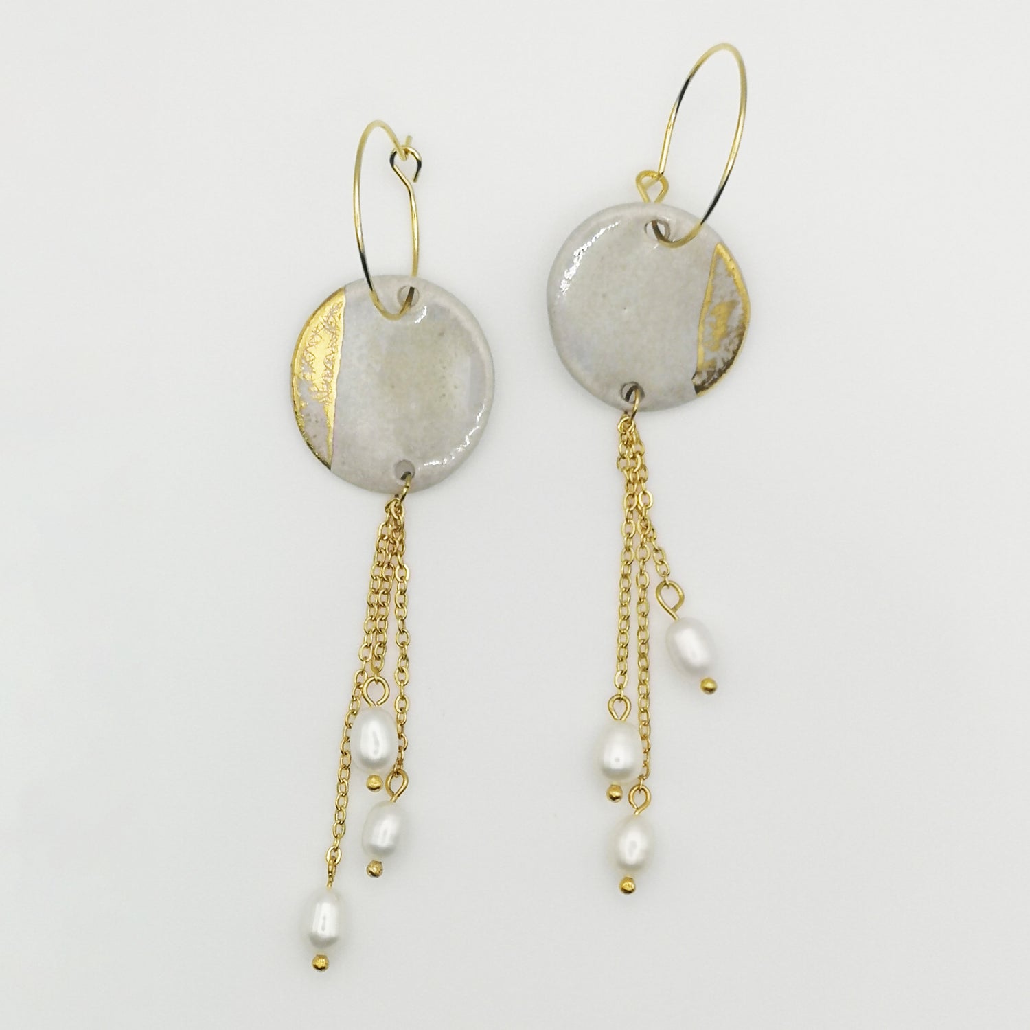 Boucles d'oreilles longues avec anneaux dorés et perles, design élégant en blanc effet nacré.