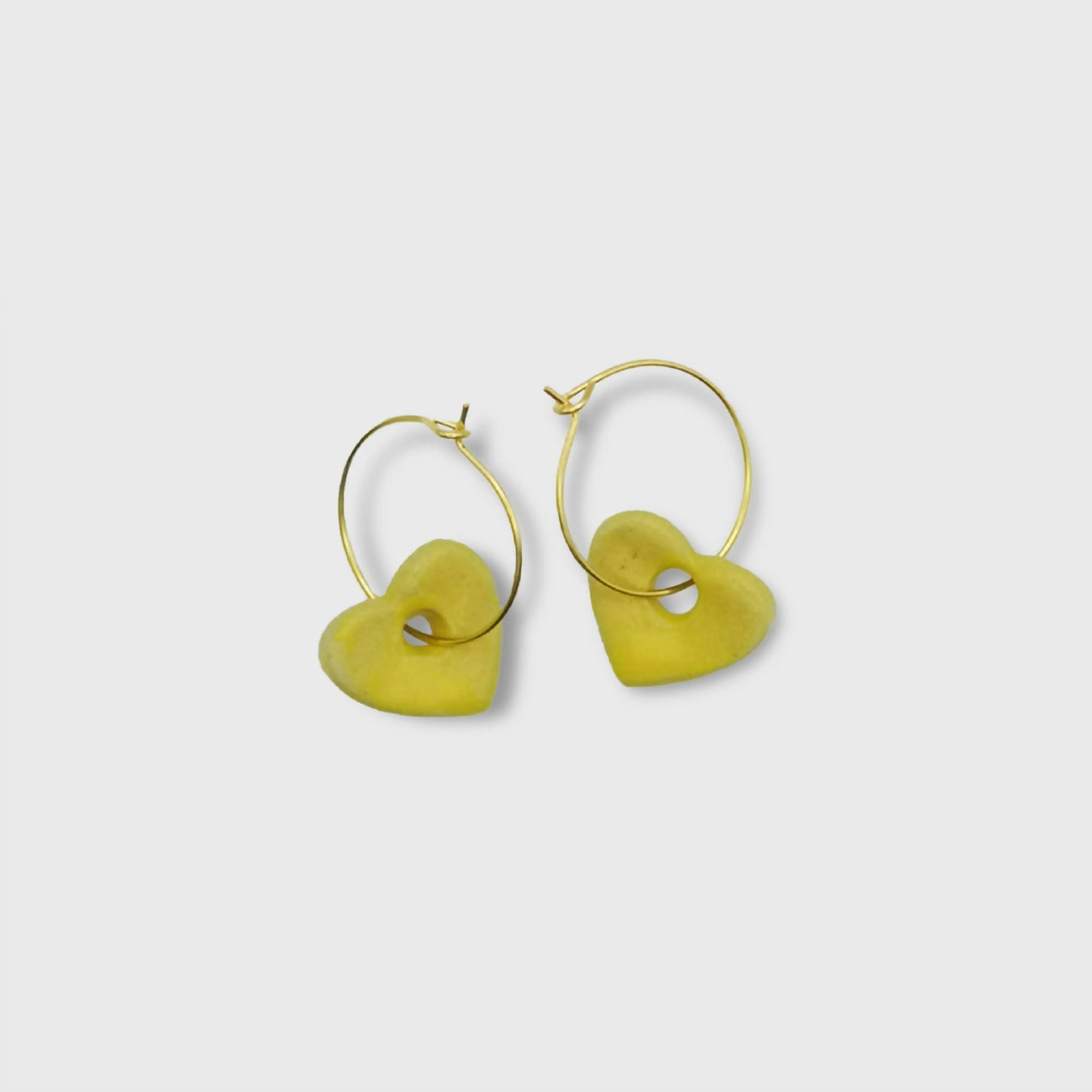 Boucles d'oreilles créoles cœurs jaune vif en céramique, capturant l'éclat de la céramique émaillée et la finesse des créoles dorées. Idéales pour ajouter une touche de couleur lumineuse à toute tenue.