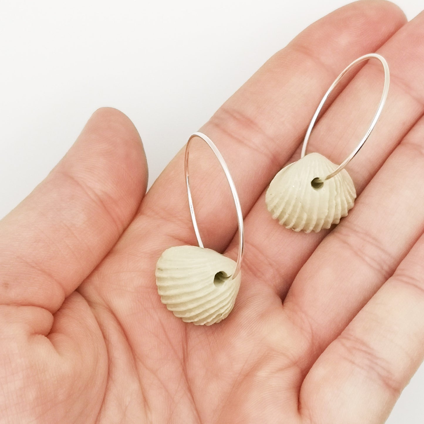 Paire de boucles d'oreilles coquillage blanches, légères et élégantes, parfaites pour un look estival, présentées dans un écrin rose Corinne Céramique.