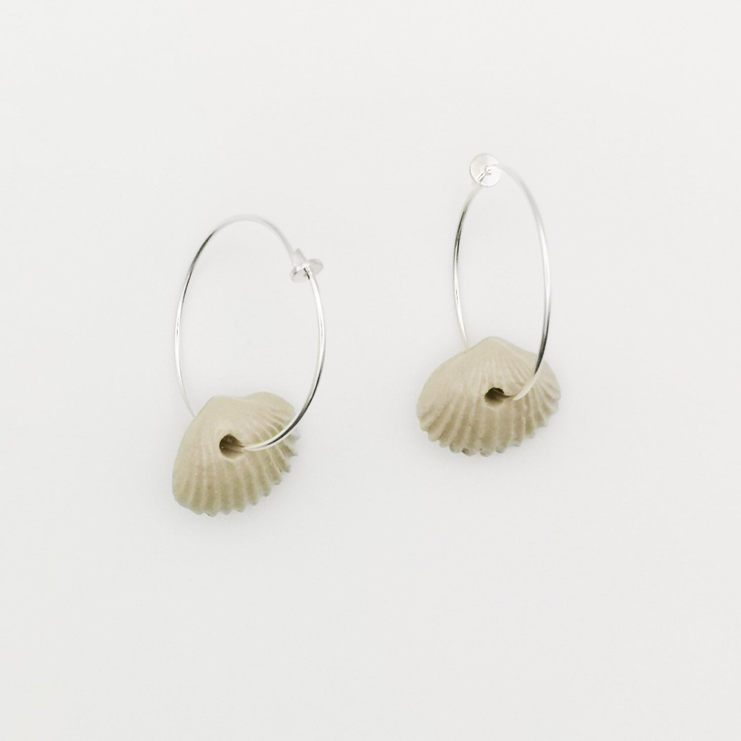 Boucles d'oreilles pendantes en céramique blanche en forme de coquillage avec anneau en argent 925, fabriquées artisanalement en Provence.