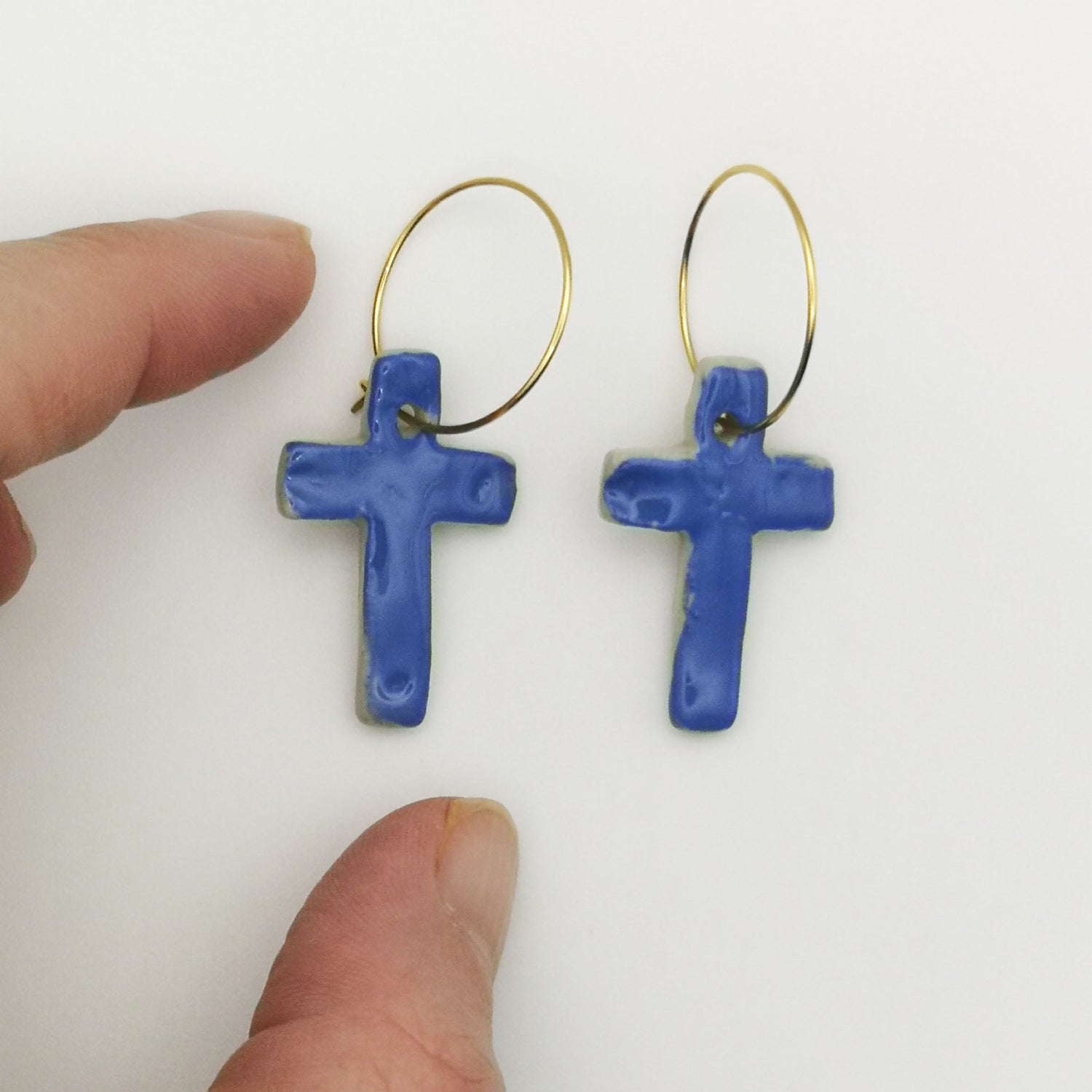 Détail de boucles d'oreilles croisées bleu roi, créoles dorées en laiton et céramique émaillée