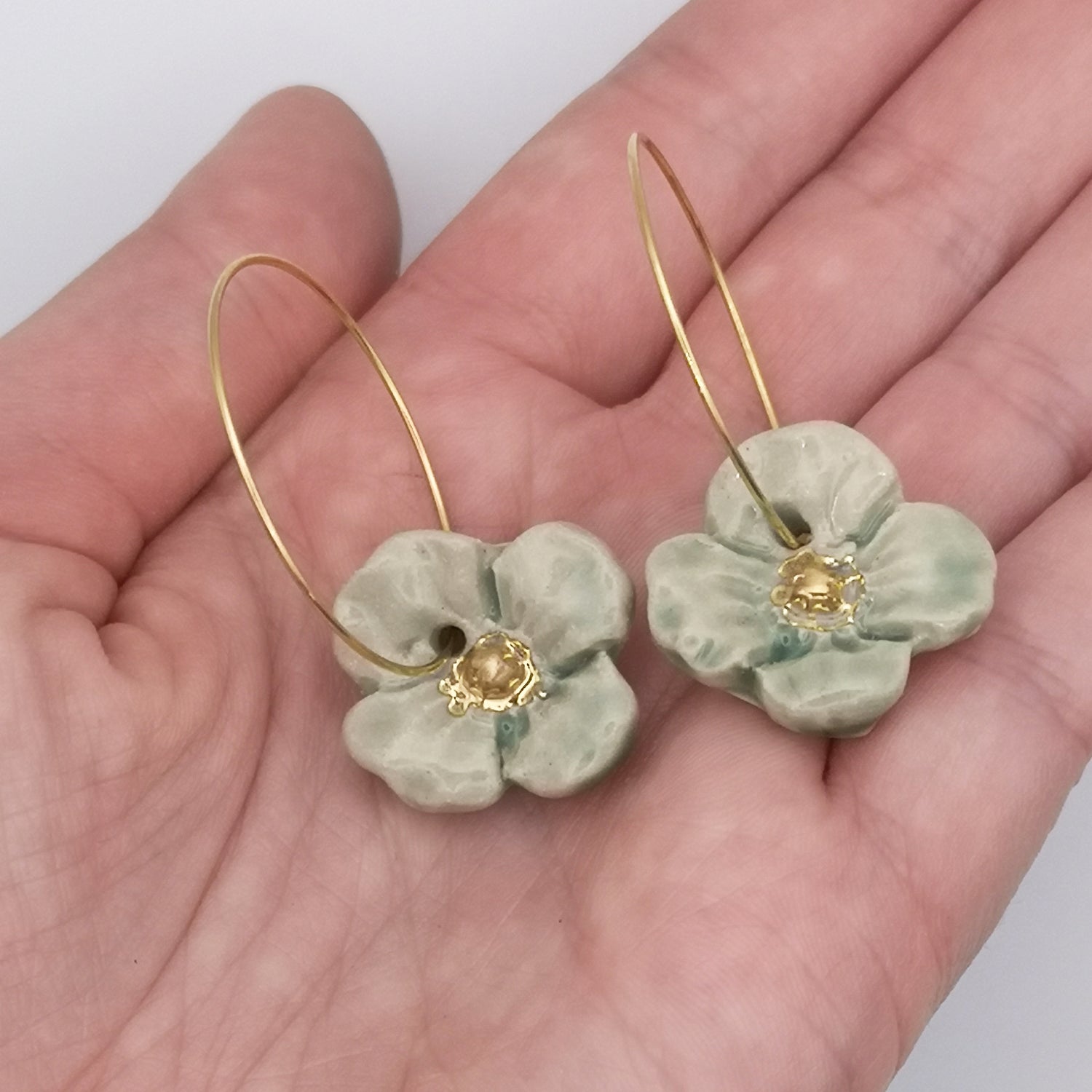 Boucles d'oreilles fleur vert or pendante vert et or pour femme dans main
