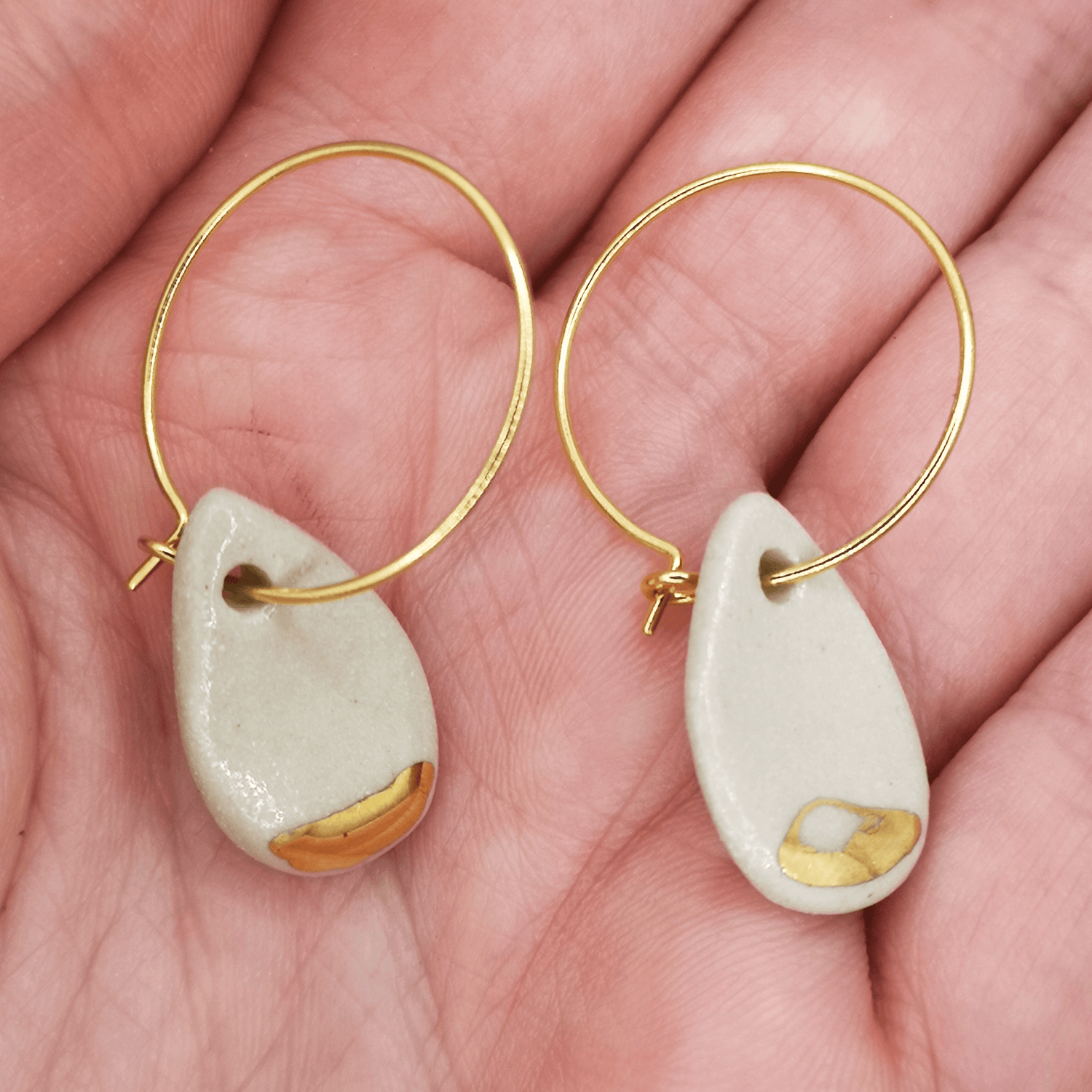 Boucles d'oreilles goutte blanc et or pendante pour femme sur main