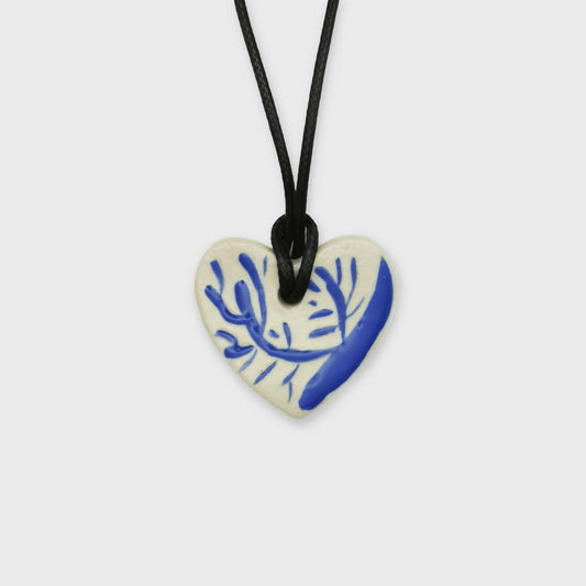 Collier cœur blanc et bleu avec motif de branche dorée, cordon en cuir réglable, bijou artisanal d’exception fabriqué à Aix-en-Provence par Corinne Céramique, parfait comme cadeau d’anniversaire élégant et unique.