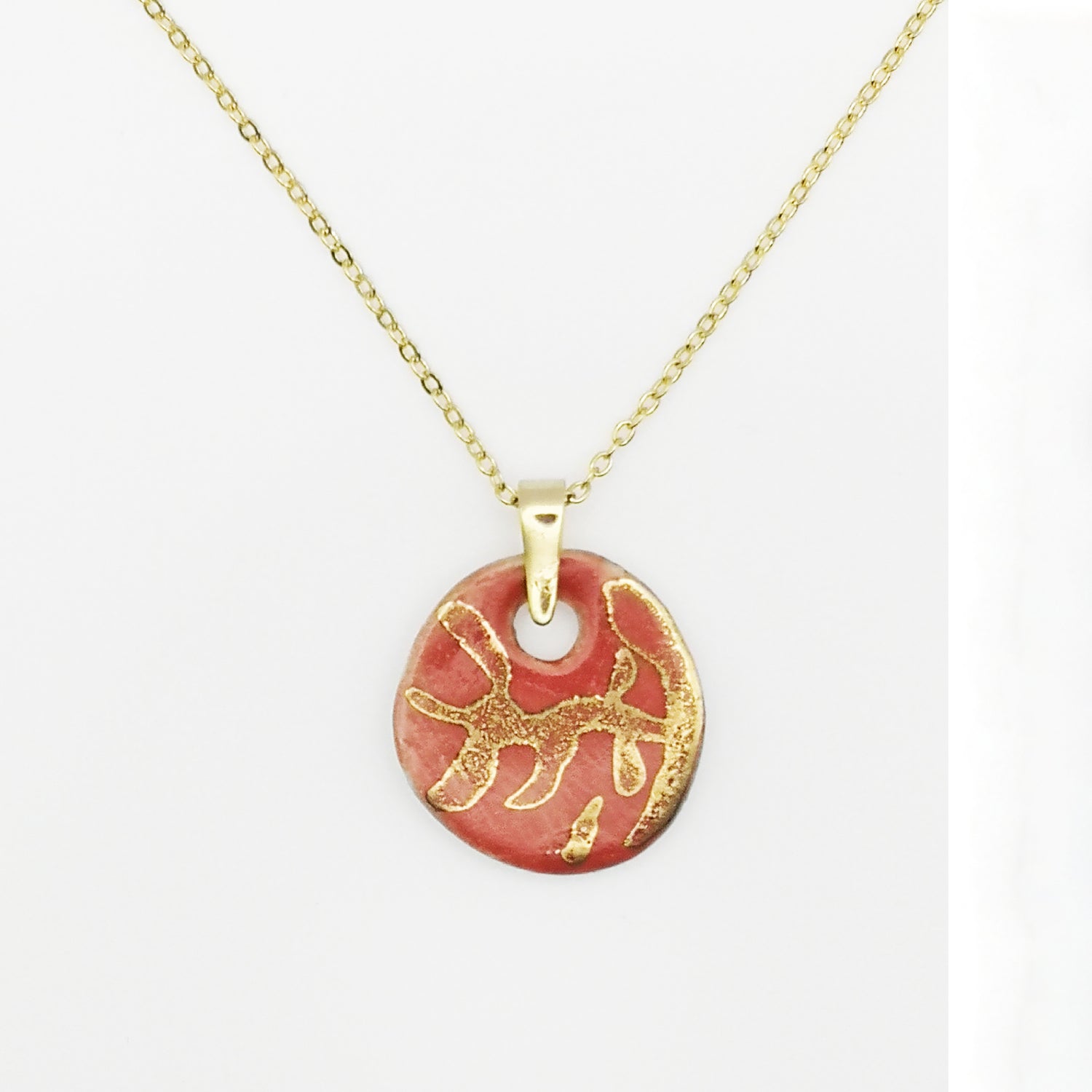 Collier en céramique rouge corail avec médaillon orné d'un motif de branches en or véritable, parfait pour ajouter une touche d'élégance naturelle.