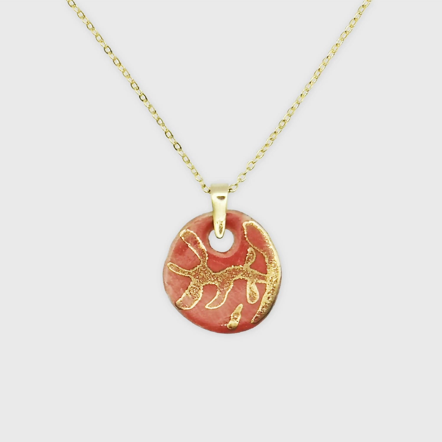 Collier en céramique rouge corail avec médaillon orné d'un motif de branches en or véritable, parfait pour ajouter une touche d'élégance naturelle.Fait mains Aix en Provence. Idee cadeau femme