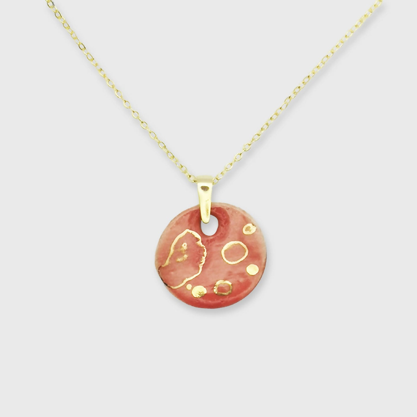 Collier médaillon rouge corail avec motif de pois dorés, bijou artisanal chic en céramique fabriqué en Provence par Corinne Céramique.