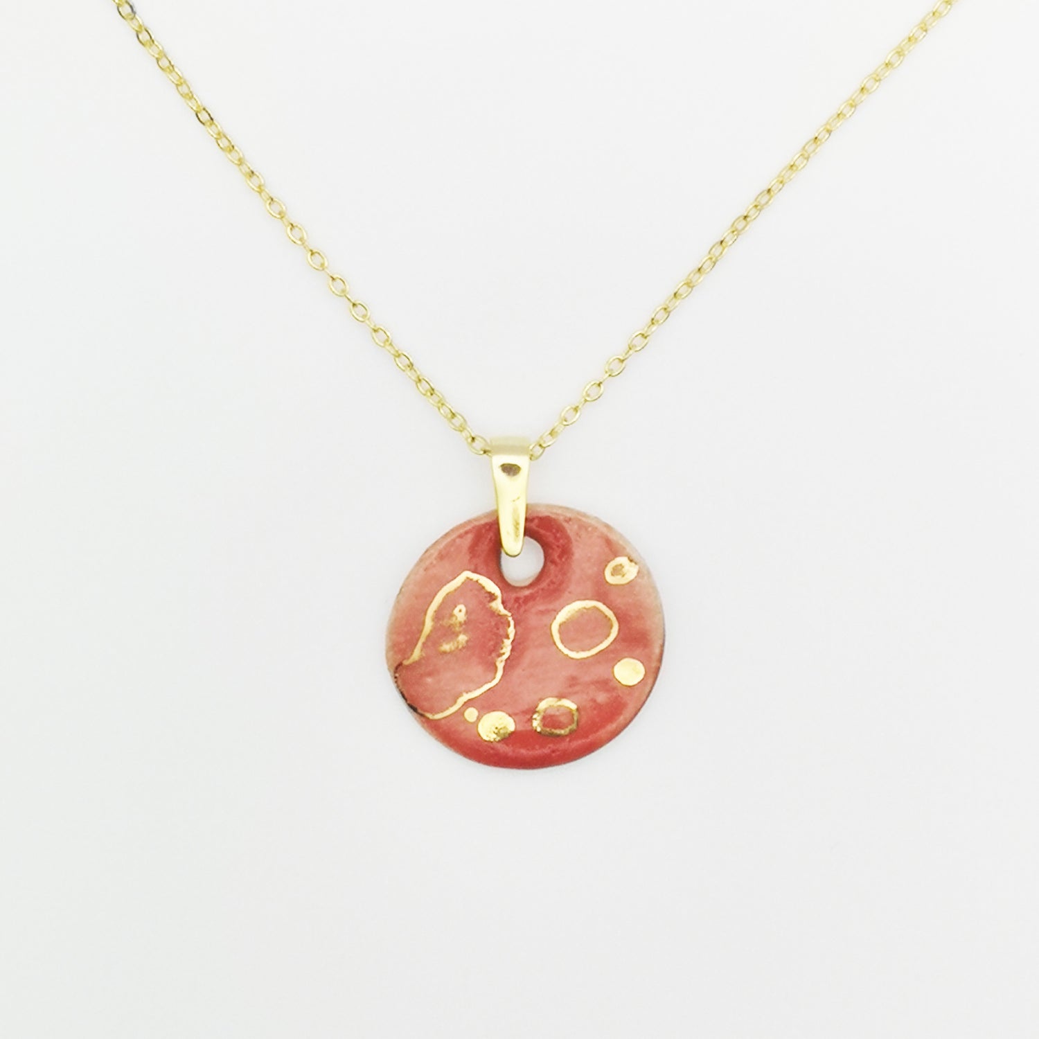 Collier médaillon rouge corail avec motif de pois dorés, bijou artisanal chic en céramique fabriqué en Provence par Corinne Céramique.