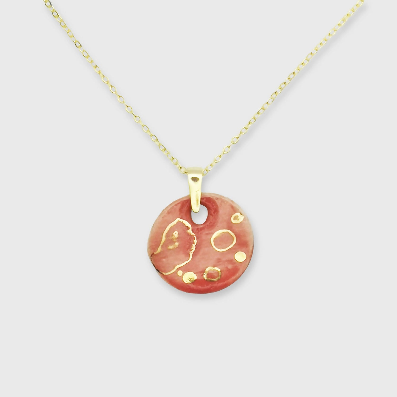 Collier médaillon rouge corail avec motif de pois dorés, bijou artisanal chic en céramique fabriqué en Provence par Corinne Céramique.