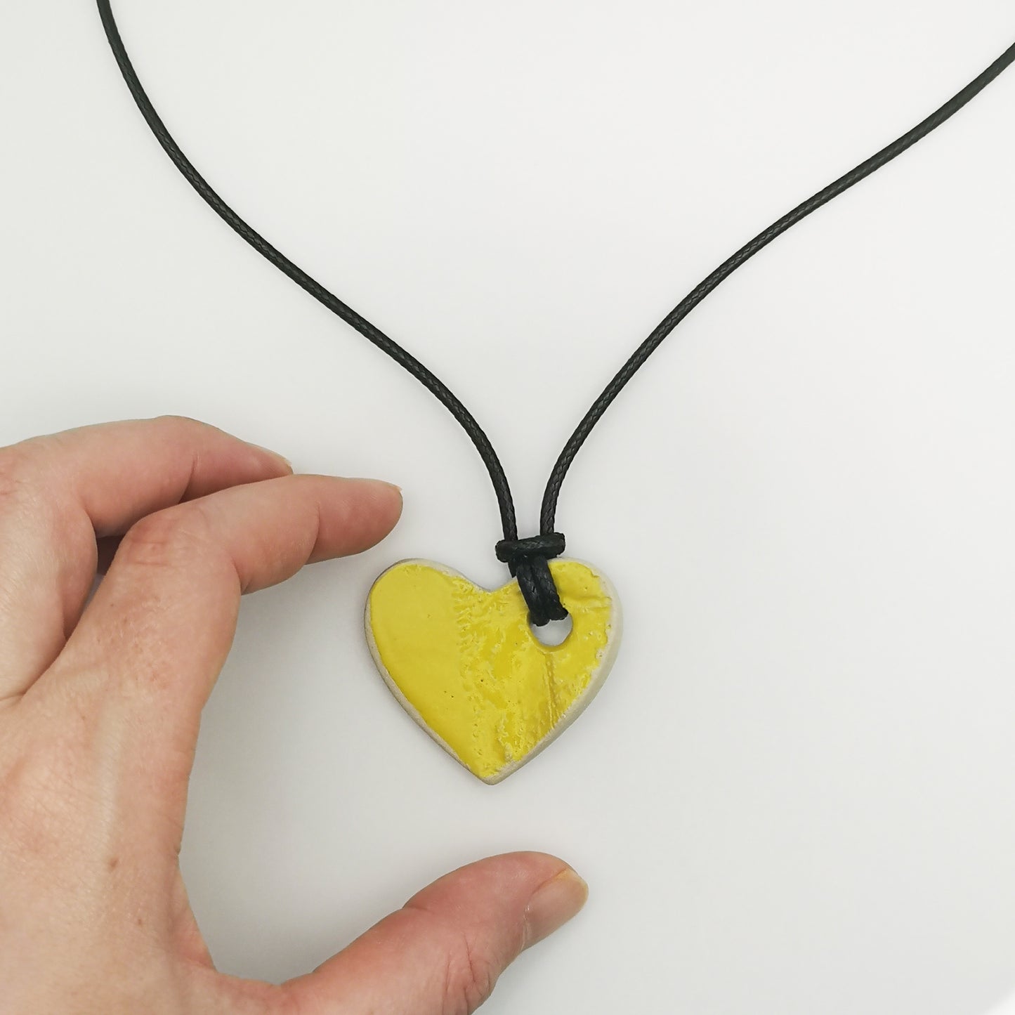 Vue rapprochée d'un pendentif en forme de cœur jaune, mettant en valeur les détails des motifs gravés à la main.