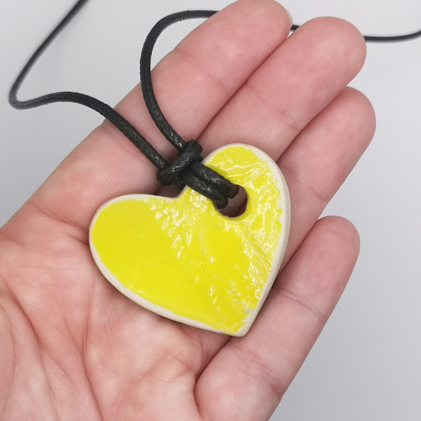 Collier cœur jaune avec un éclat lumineux, porté autour du cou, illustrant son élégance et sa légèreté.