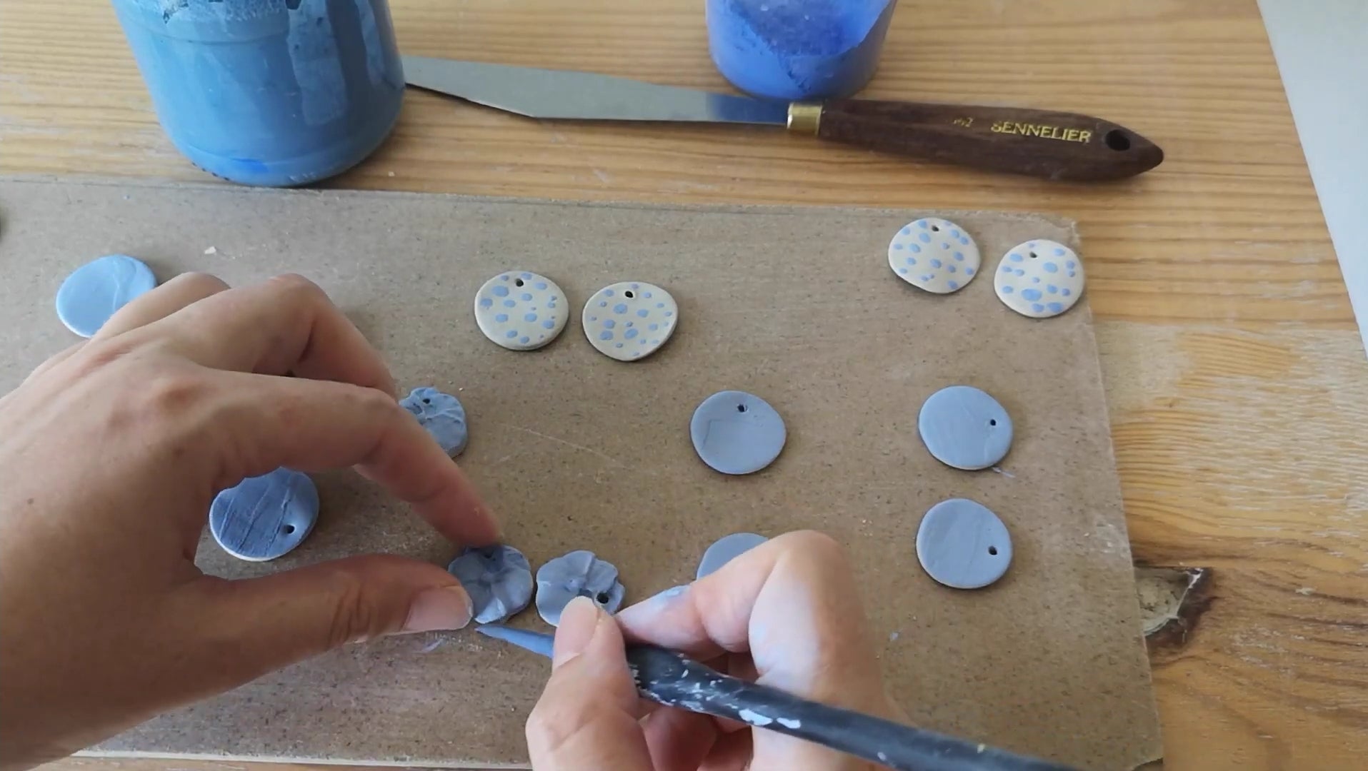 Charger la vidéo : Fabrication artisanale des bijoux Corinne Céramique. Chaque bijoux est 100% fait main en Provence. On peut voir le façonnage, la peinture et les cuissons des pendentifs en céramique..