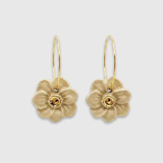 Boucles d’oreilles fleurs en céramique beige avec centre doré, présentées sur fond gris clair. Corinne Céramique