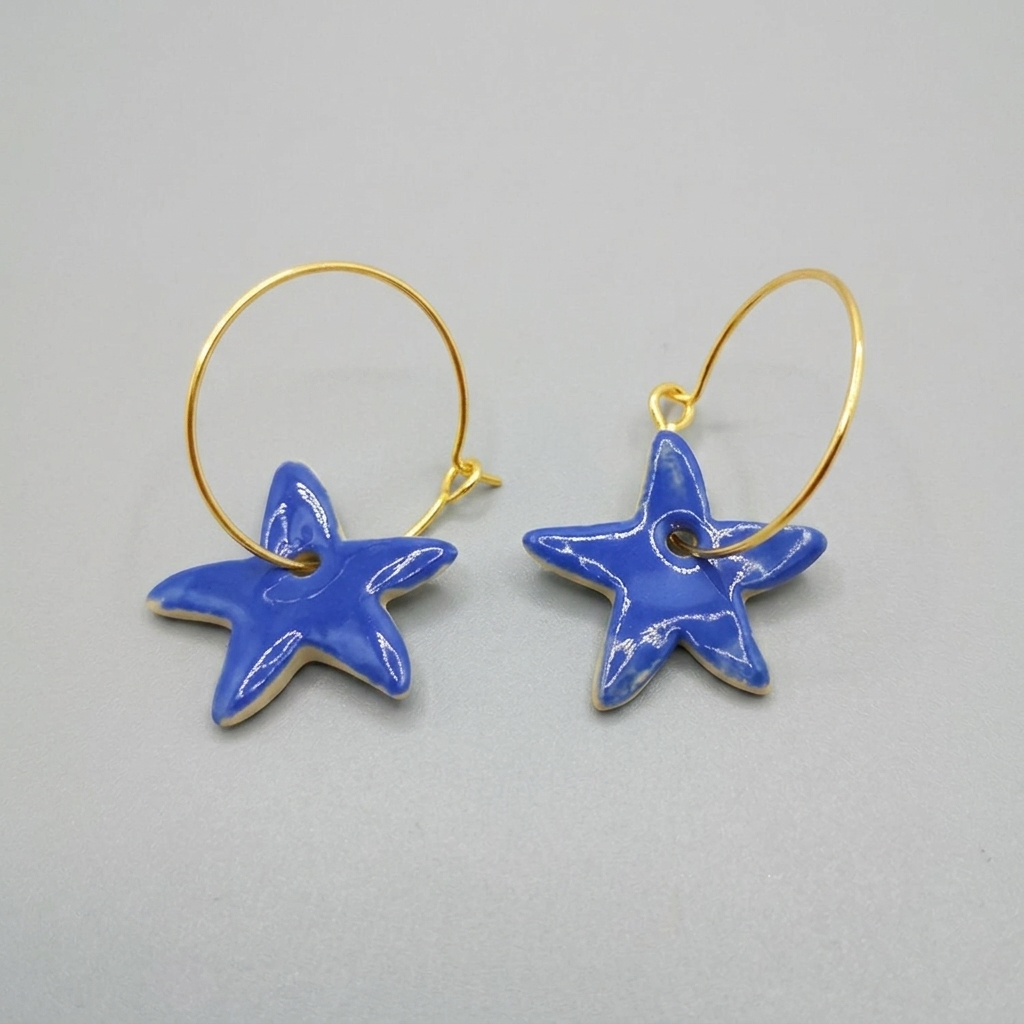 Boucles d’oreilles étoile bleue en céramique émaillée sur anneaux gold filled, bijou artisanal fait main par Corinne Céramique.