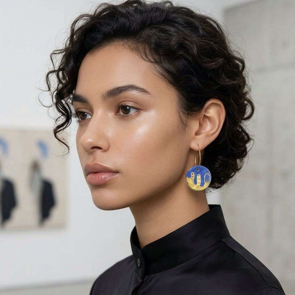 Femme élégante et chic portant des boucles d’oreilles Corinne Céramique bleu et or inspirées de Matisse lors d’un vernissage