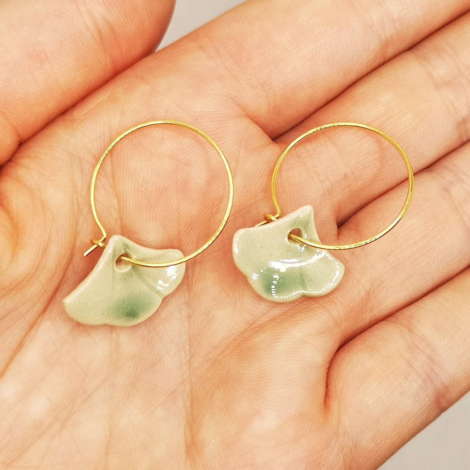 Boucles d'oreilles Ginkgo pendante verte pour femme dans une main